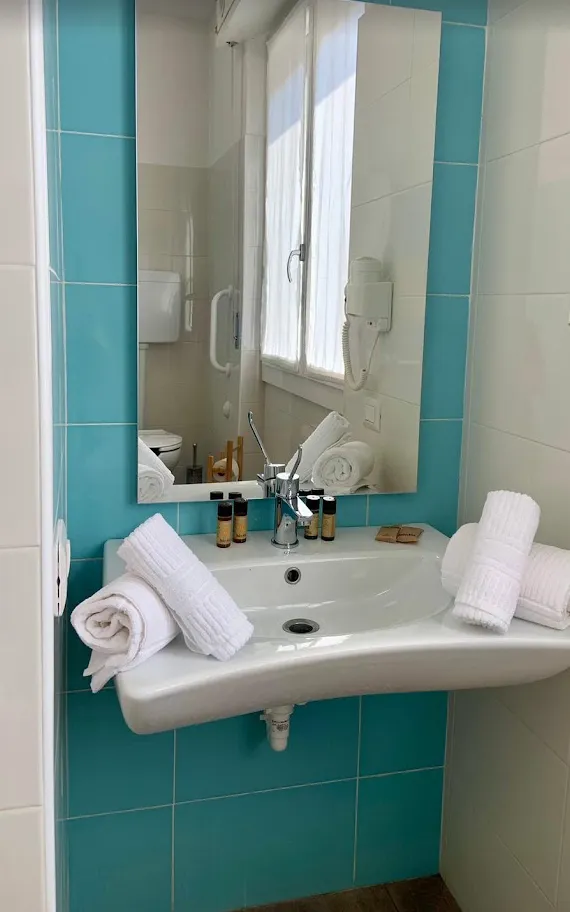 Un bagno con le piastrelle azzurre, asciugamani e cortesie