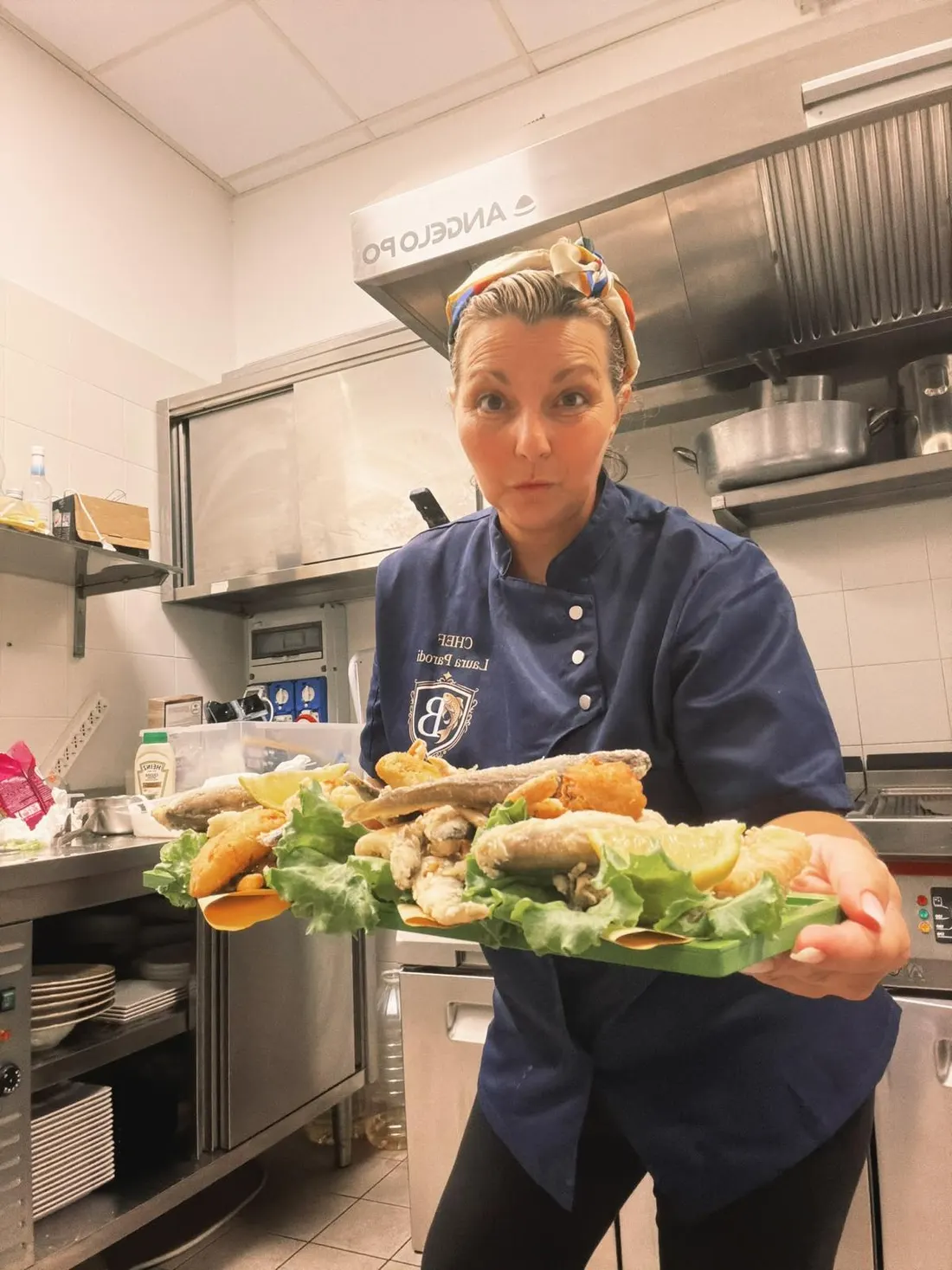 La chef Laura in cucina con un vassoio di pesce